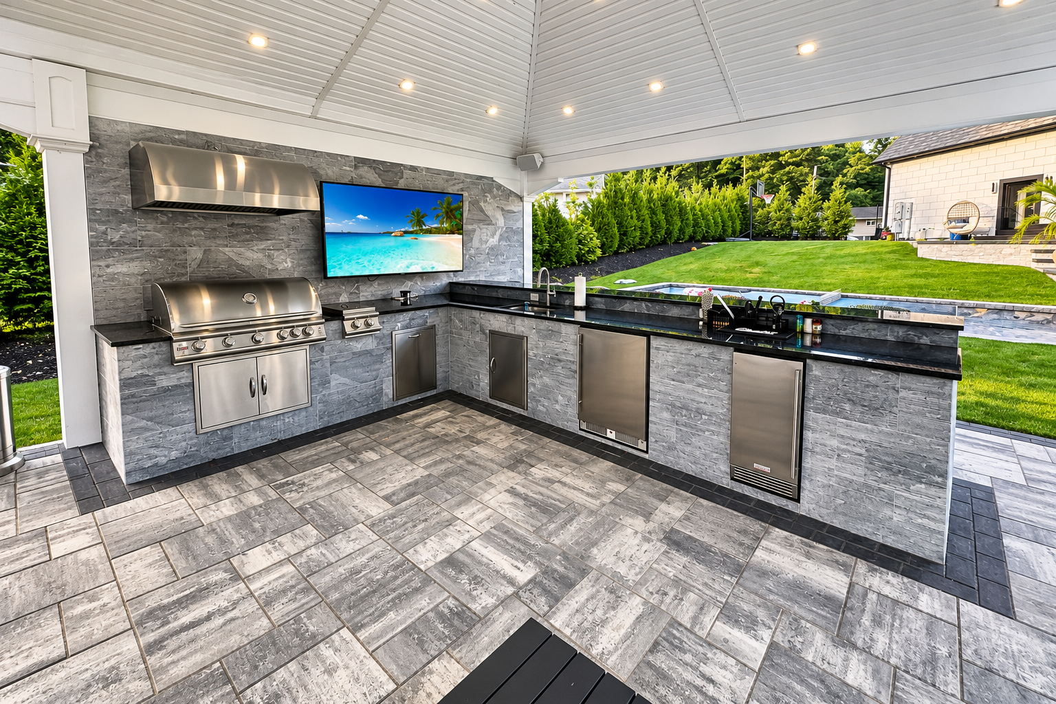 Covered outdoor BBQ kitchen with stone veneer, granite counters and grey paver patio